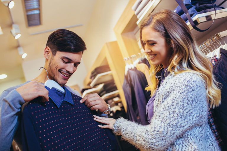 Young man consults with girlfriend while selecting a sweater